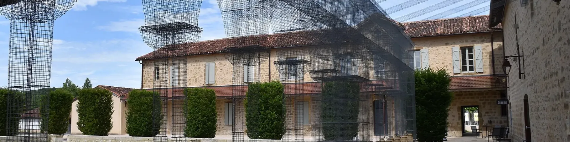 Évocation contemporaine du cloître : arcades en structures grillagées dans le jardin